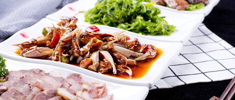 A variety of dishes including sliced meat, stir-fried vegetables, and greens, served on white plates.