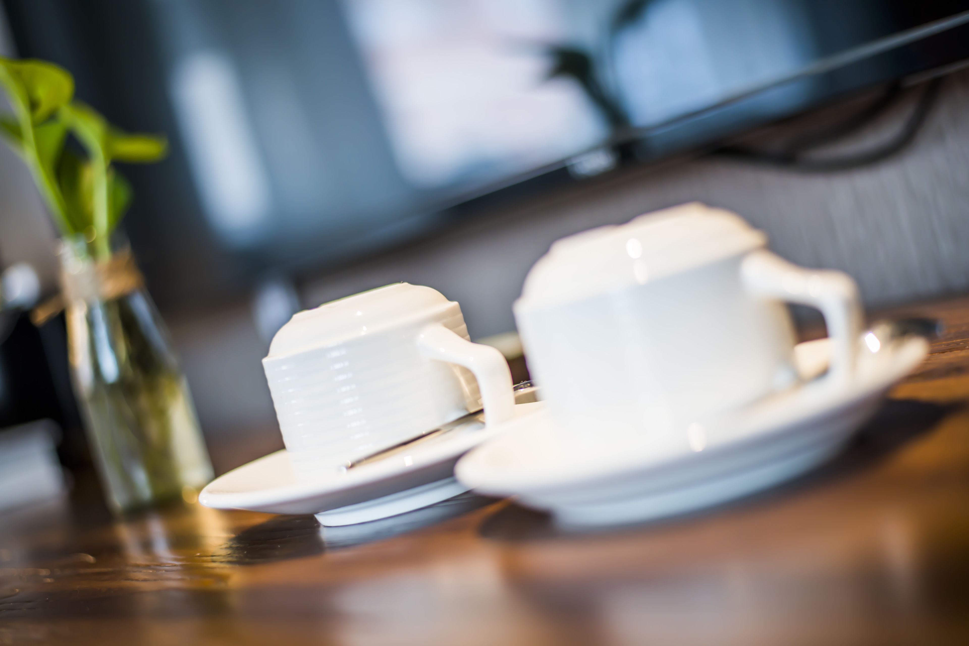 A close-up of a white teacup and saucer on a wooden table.