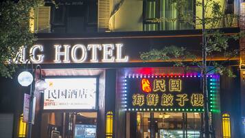 Exterior del Hotel LG con señalización iluminada, incluyendo un letrero de neón con caracteres chinos y un farol tradicional.