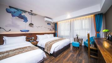 Habitación de hotel con dos camas, un escritorio de madera, una mesita pequeña y una silla.