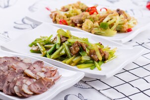 Three white rectangular plates with food, placed on a table with a grid pattern.