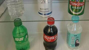 A refrigerator shelf with various beverages including a green bottle, a black bottle, and a clear bottle with a blue label.