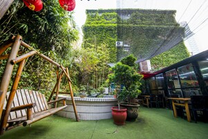 Un patio con un columpio, plantas en macetas y una zona de estar.