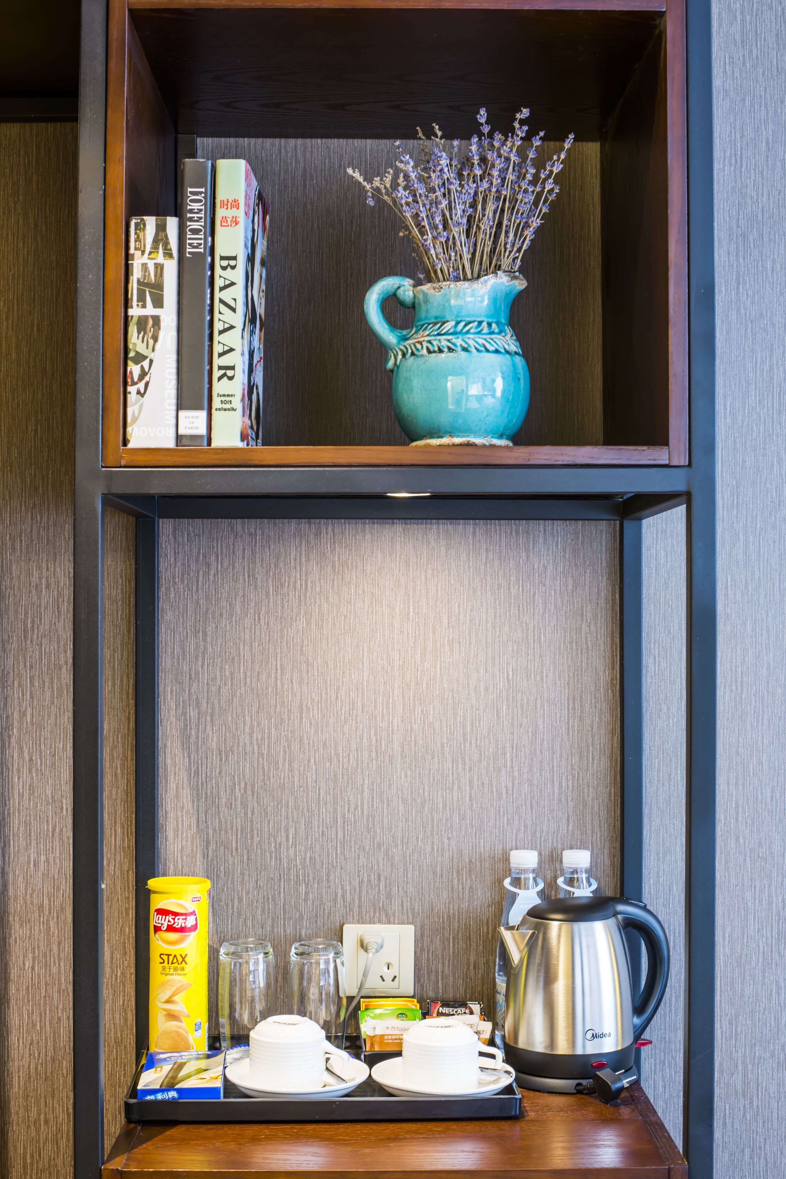 A shelf with books, a vase with lavender, and a tray with breakfast items.
