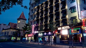 A multi-story hotel with a central tower, multiple balconies, and illuminated signage. - MG Hotel - St. Michael's Cathedral, Qingdao (Qingdao)