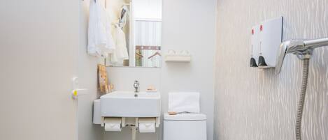 Un baño pequeño con lavamanos, inodoro y ducha blancos.
