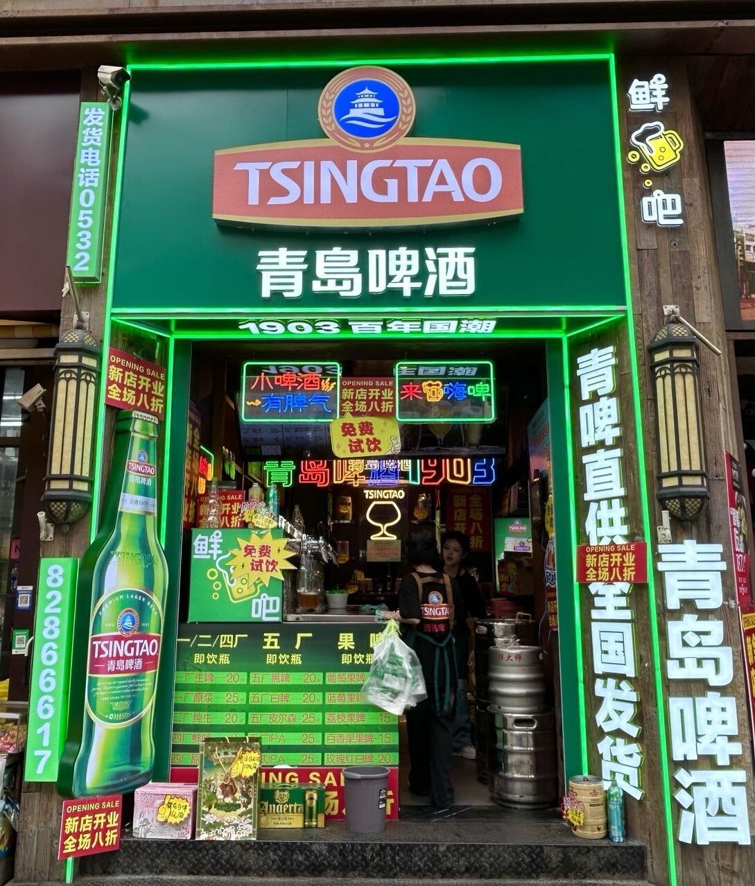 A storefront with a prominent Tsingtao beer sign, neon lights, and various promotional signs.