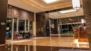 A modern lobby with a glass partition, seating area, and a chandelier. - 1 Bedroom Apartment Casa Grande Residence by Travelio (Jakarta)