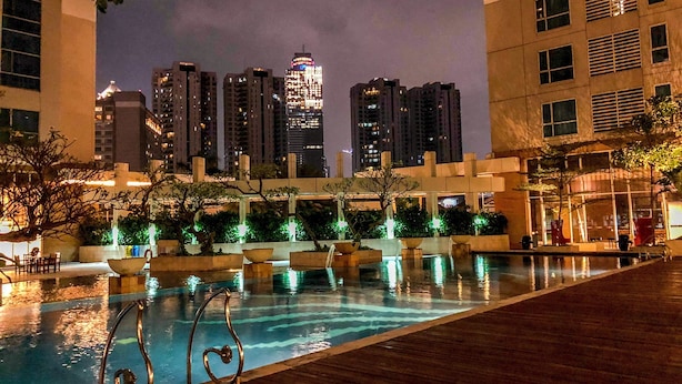 A nighttime view of a swimming pool with a city skyline in the background. - 1 Bedroom Apartment Casa Grande Residence by Travelio (Jakarta)