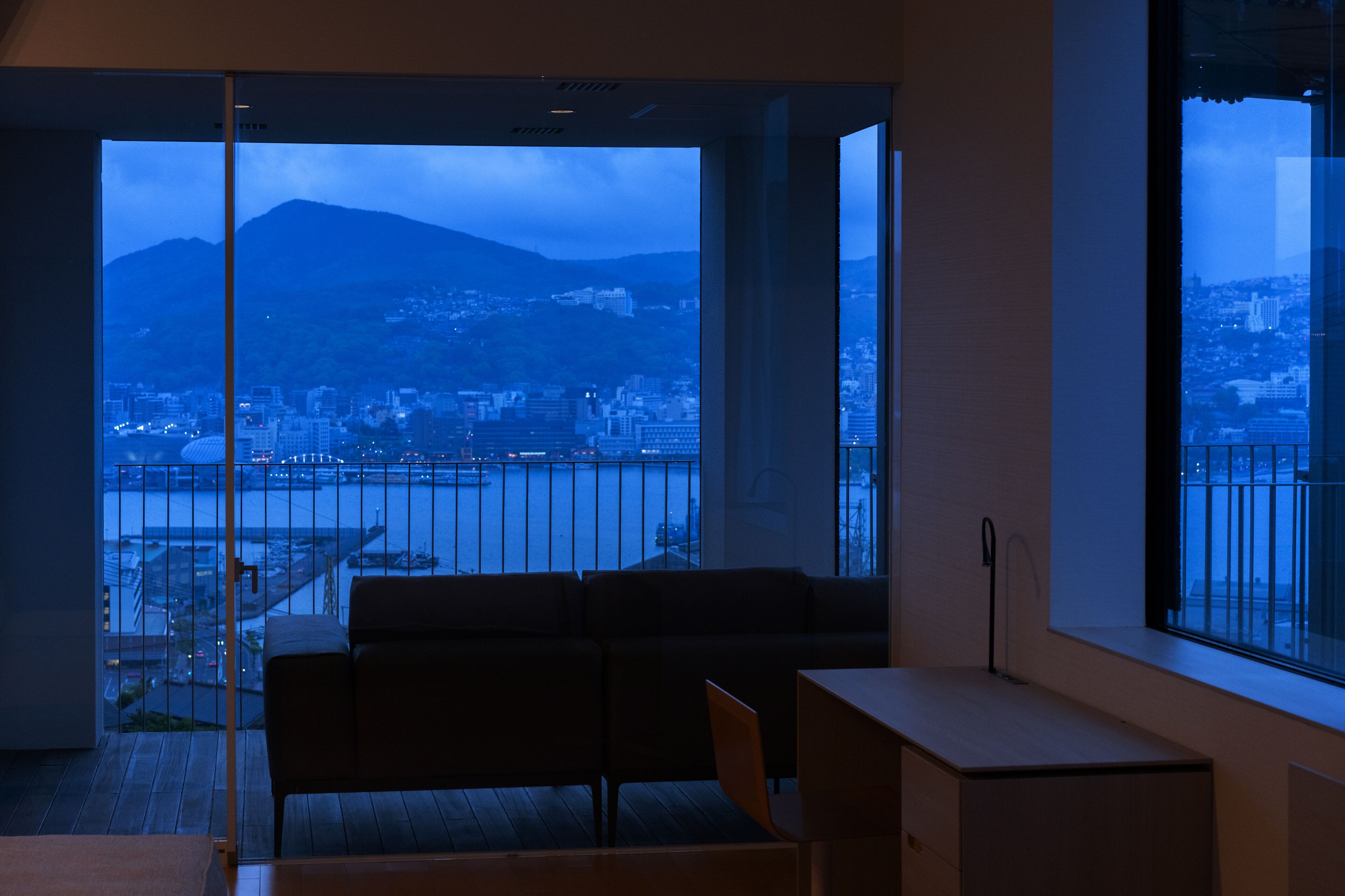 A modern room with a large window offering a view of a cityscape and a mountain.