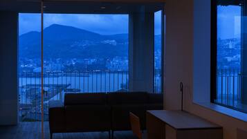 A modern room with a large window offering a view of a cityscape and a mountain.