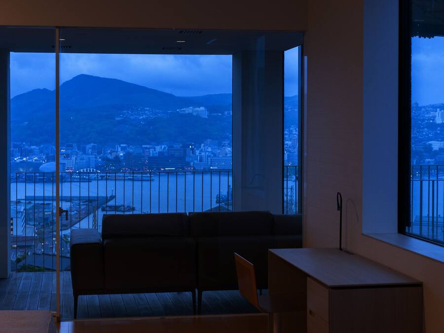 A modern room with a large window offering a view of a cityscape and a mountain.