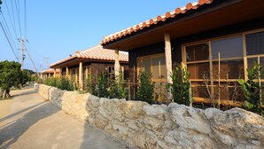 A row of traditional-style buildings with stone walls and tiled roofs. - Tabinoteitaku OkinawaNakijin HOMANN CONCEPT (Nakijin)