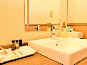 A hotel bathroom with a large white sink, a mirror, and toiletries on the counter. - Kose Onsen Hotel (Karuizawa)