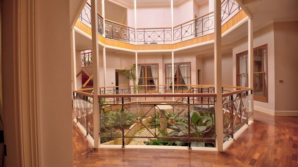 A multi-level atrium with a central garden, glass railings, and wooden flooring. - The Round House ~Truly Unique ~ Sleeps 14 ~ Close to CBD and Mount Panorama!
 (Bathurst)