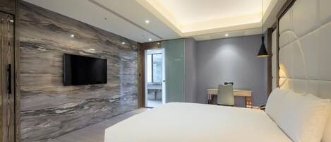A modern bedroom with a large bed, a flat-screen TV mounted on a marble wall, and a small desk with a chair.