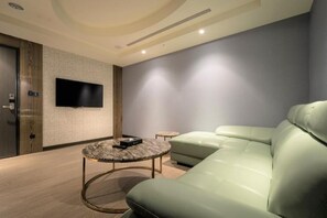 Un salon moderne avec un canapé, une table basse et un téléviseur à écran plat fixé au mur.