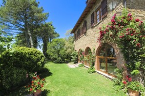 Un edificio de piedra con jardín, cielo despejado y un camino que lleva a la entrada.