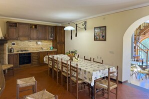 A kitchen with wooden cabinets, a dining table with chairs, and a view of a staircase leading to an outdoor area. - Beautiful villa with a splendid panoramic view over vineyards and olive groves. Ideal for visiting T (Monte San Savino)