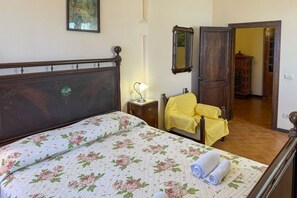 A bedroom with a bed, a nightstand, a chair, a mirror, and a door leading to another room. - Beautiful villa with a splendid panoramic view over vineyards and olive groves. Ideal for visiting T (Monte San Savino)
