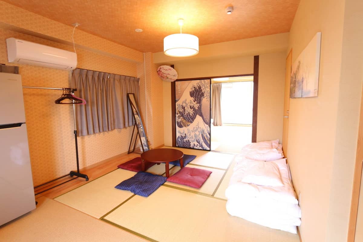A traditional Japanese room with tatami flooring, a futon bed, a low table, and a sliding door.