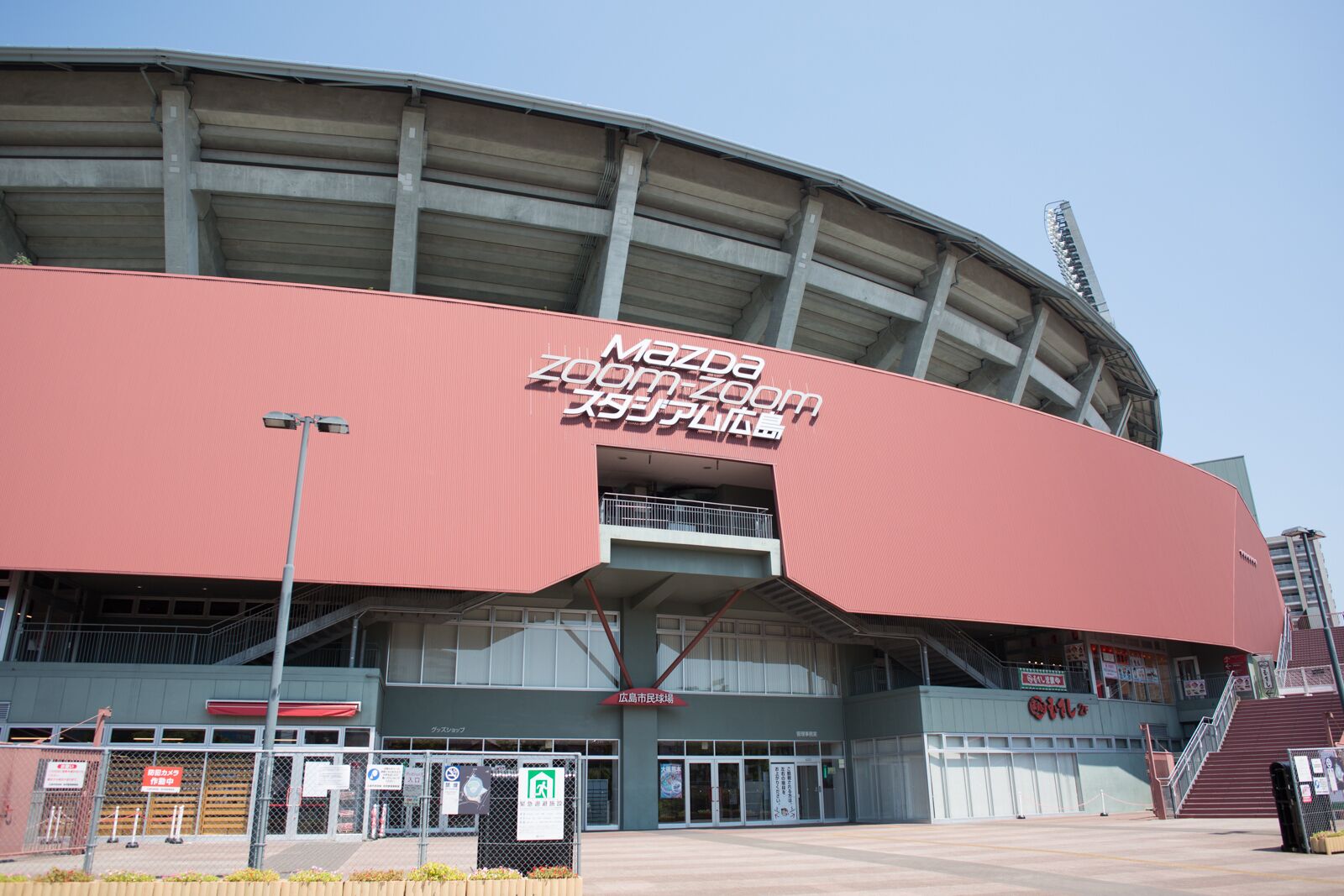 A large stadium with a prominent red exterior and signage in multiple languages.