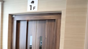 A wooden elevator door with a sign above it indicating the first floor. - RED HELMET House＆Sports Bar Hiroshima - Hostel (Hiroshima)
