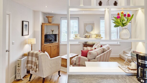 A modern living room with a sofa, a coffee table, and a television. There is a window with blinds, a fireplace, and a bookshelf with decorative items. - Castleton , Chichester  - sleeps 2 guests  in 1 bedroom (Chichester)