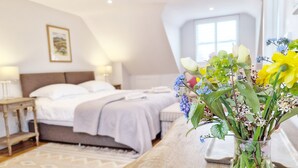 A hotel room with a bed, bedside table, and a vase with flowers. - Castleton , Chichester  - sleeps 2 guests  in 1 bedroom (Chichester)