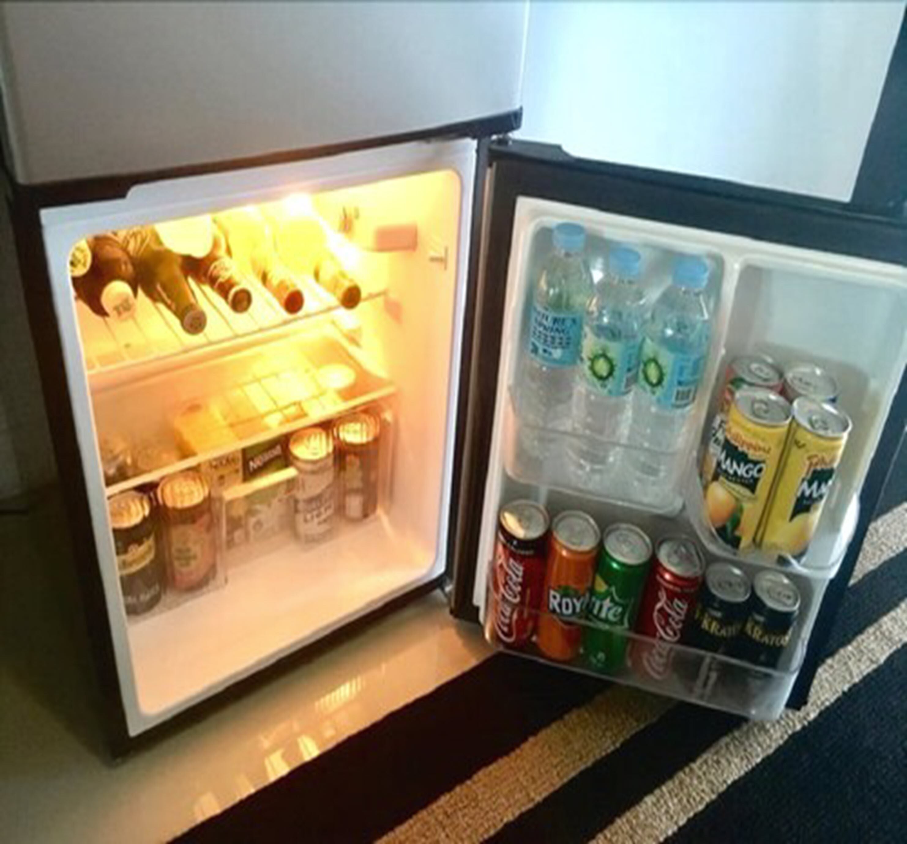 A mini-fridge with various beverages including water, soda, and juice.