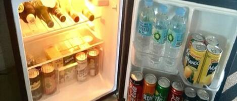 A mini-fridge with various beverages including water, soda, and juice.