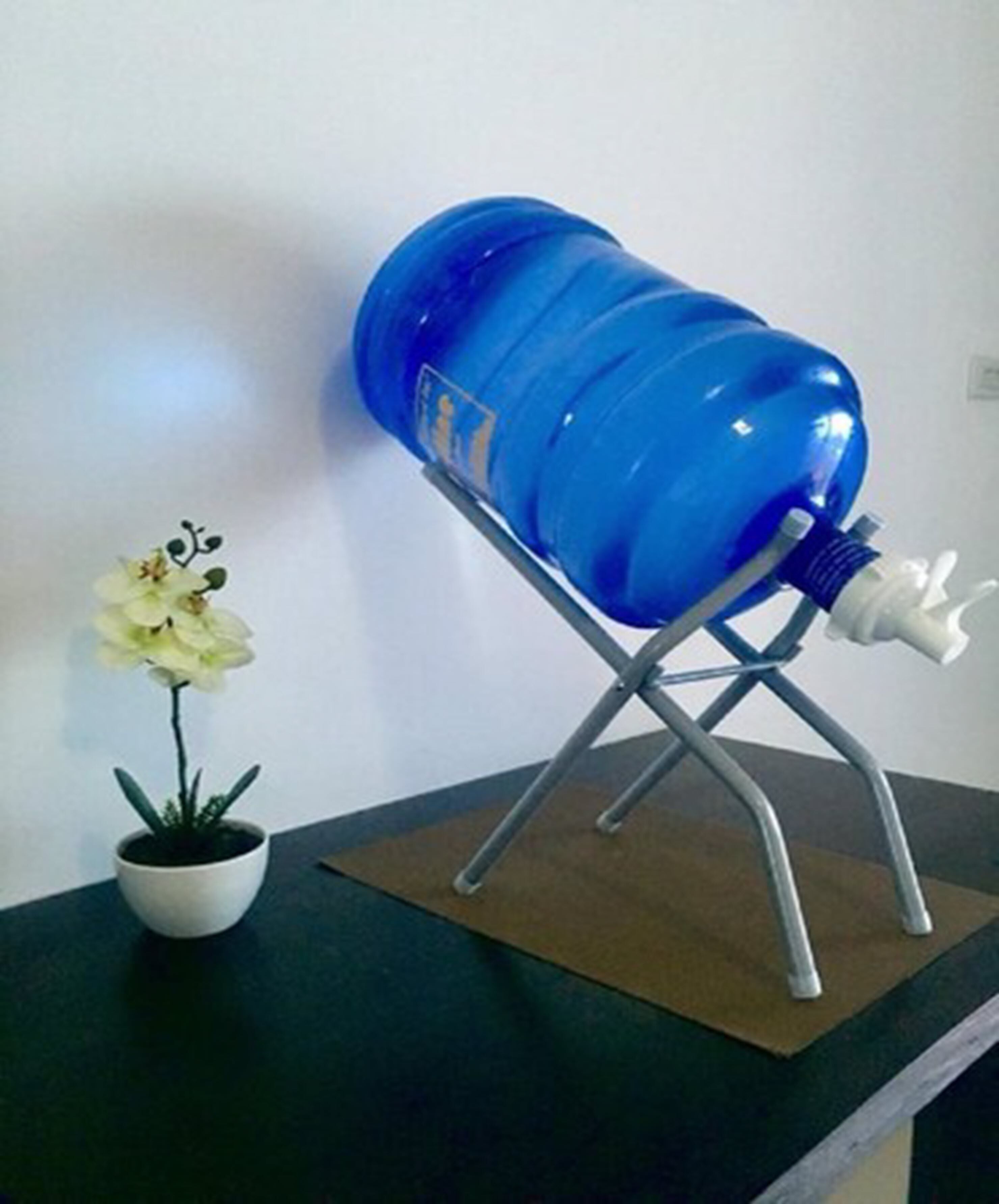 Un distributeur d’eau bleu, posé sur un support métallique, avec une fleur blanche dans un pot à côté.