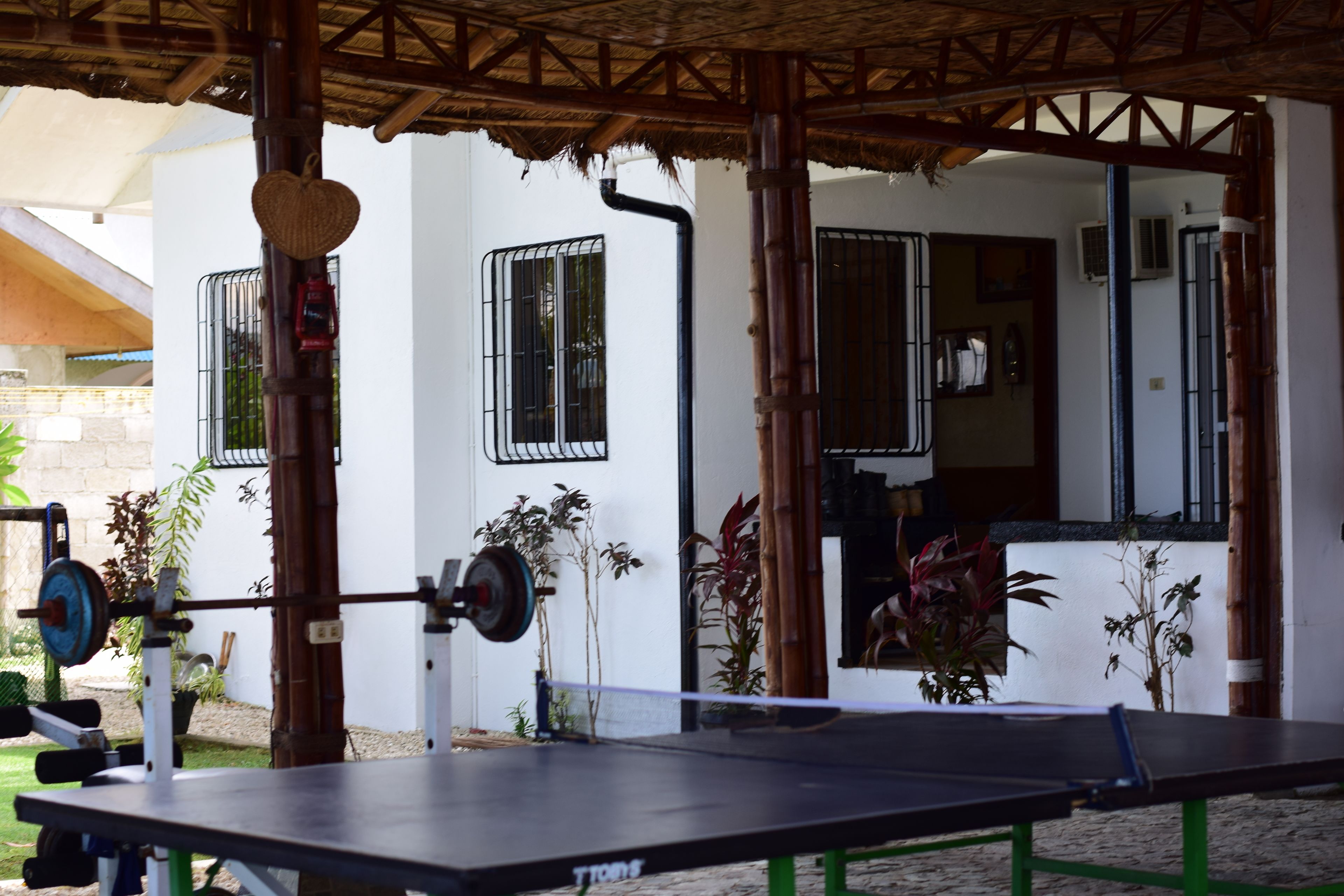 A covered outdoor area with a table, a barbell, and weight plates.