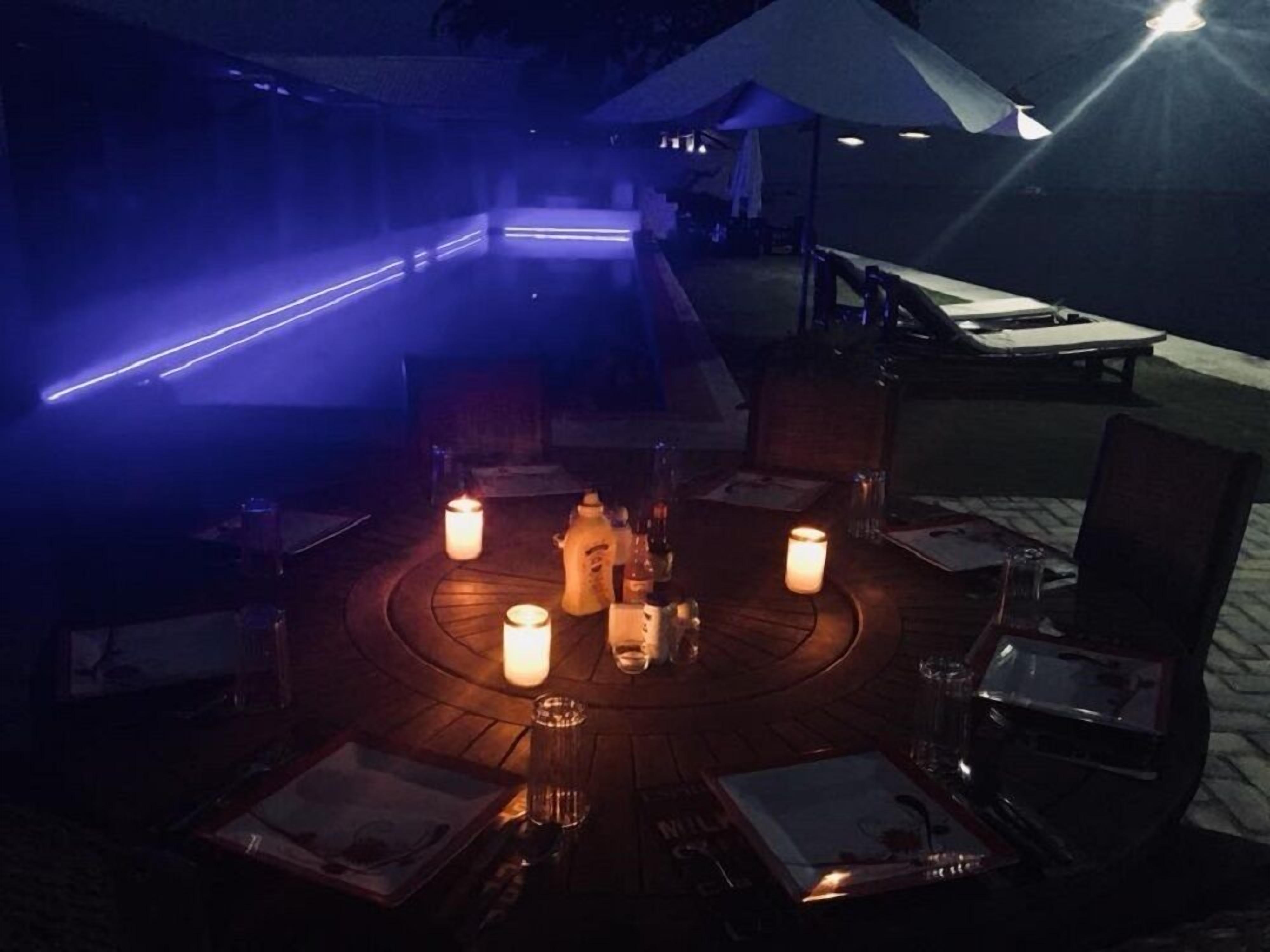 An outdoor dining area with tables set for two, surrounded by candles and under a tent.