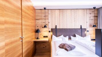 Et moderne hotelværelse med en trævæg, en seng med hvide sengetøj, et natbord og to hængende lamper.