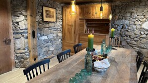 A rustic dining area with a wooden table, stone walls, and hanging light fixtures. - Double room de luxe - alpen hotel post **** (Au)
