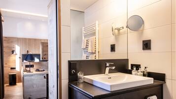 A modern bathroom with a large sink, mirror, towel rack, and a small glass on the counter.