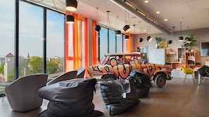 Un interior moderno con ventanas amplias, un coche con grafitis coloridos y zonas de estar.