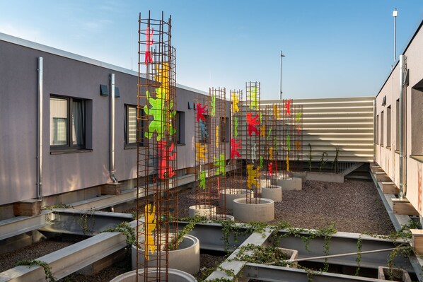 A rooftop terrace with concrete planters and a metal structure with colorful elements. - Holiday Inn - the niu, Hide Berlin Friedrichshain by IHG (Berlin)