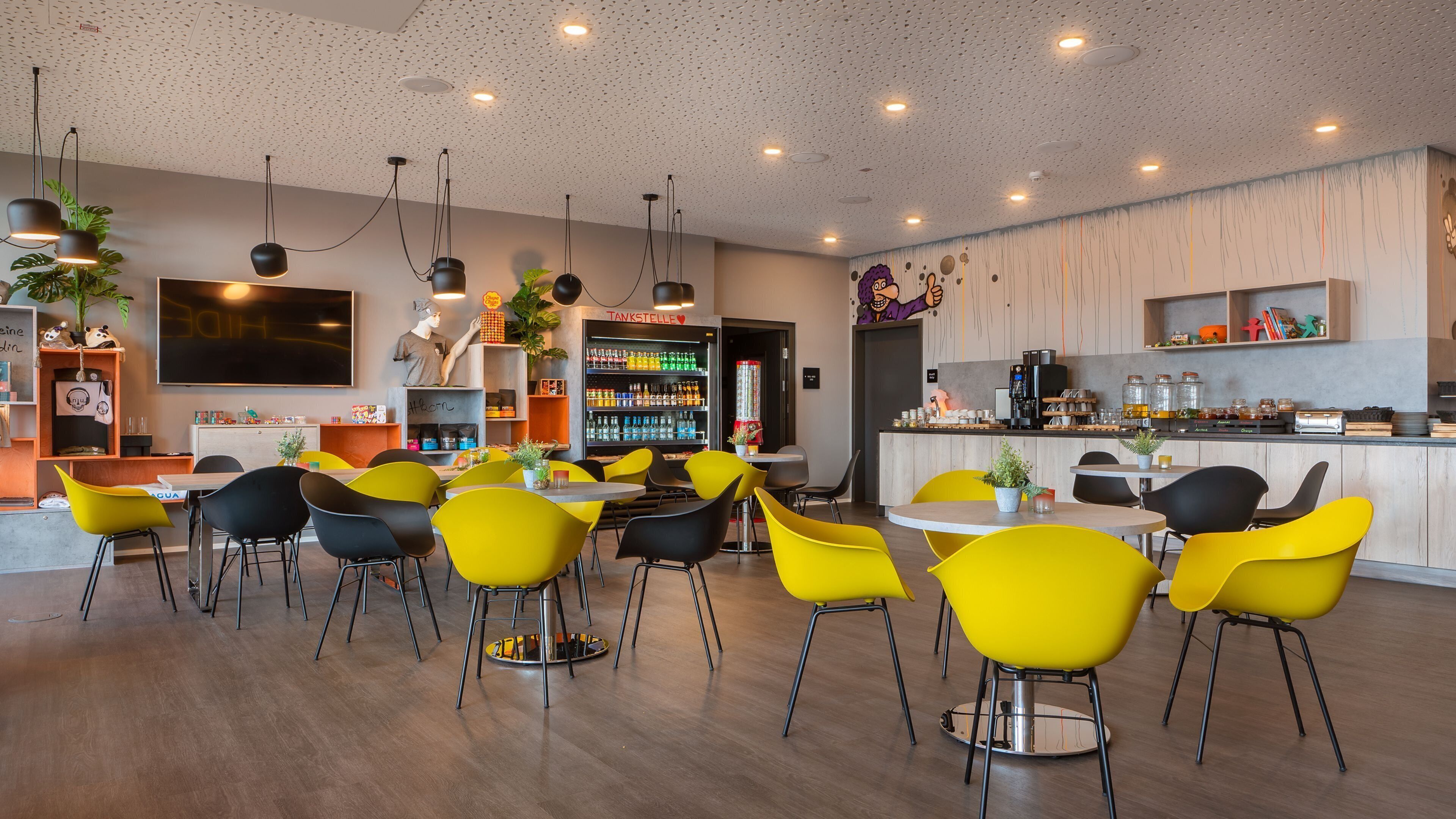 A modern cafe with yellow and black chairs, a bar area, and a variety of seating options.