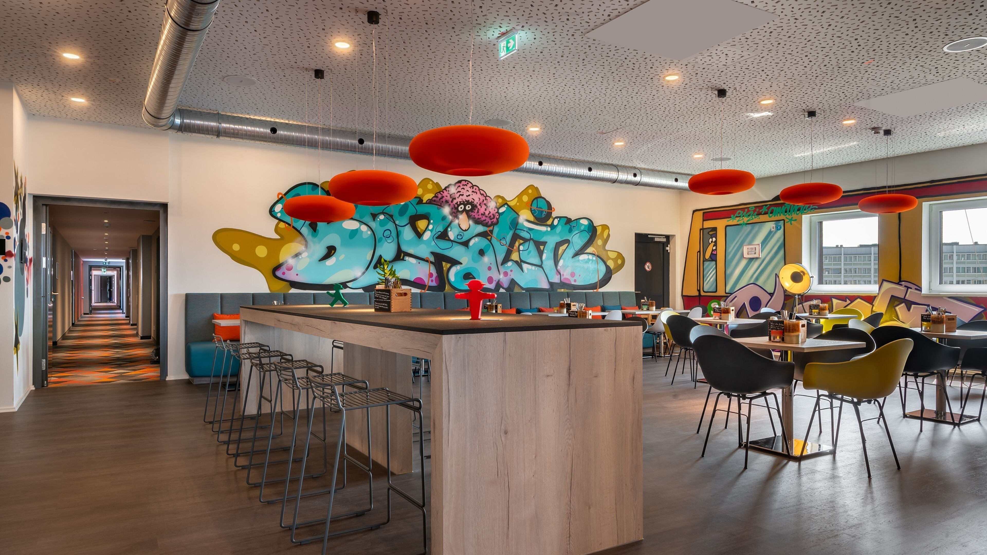 A modern interior with a central bar area, seating arrangements, and a graffiti wall.