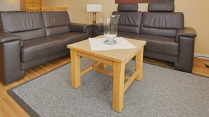 A living room with two brown leather sofas, a wooden coffee table, a glass vase, and a sunset painting on the wall. - N18K (BC.a5) - Stranddomicil Steiner (Büsum)