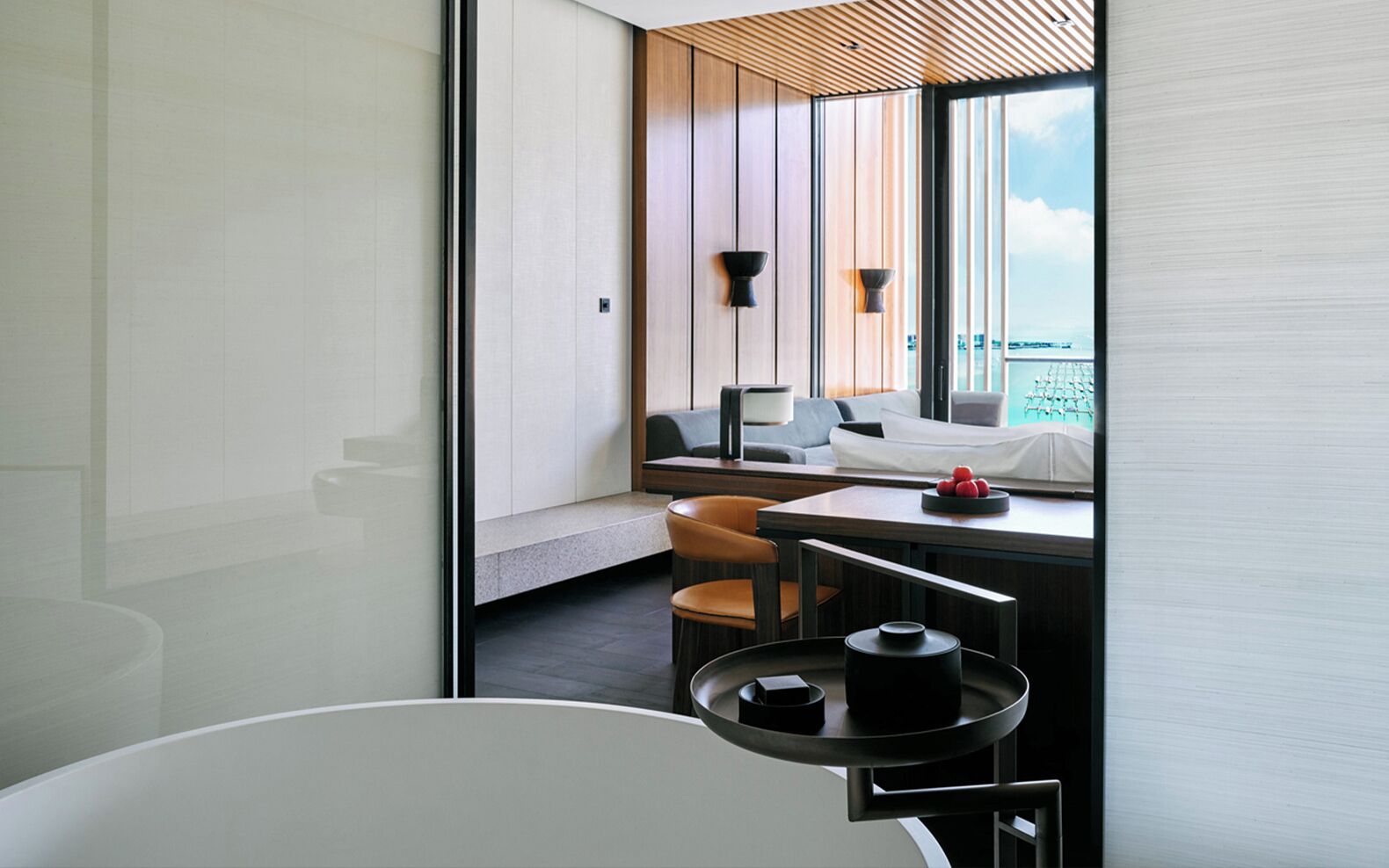 A modern bathroom with a bathtub, a vanity with a mirror, and a seating area with chairs and a table.