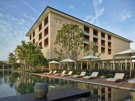Un hotel con piscina, sillones de descanso y sombrillas.