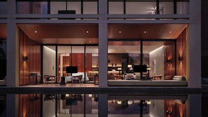 Un hotel moderno con un vestíbulo amplio, un área de comedor y un dormitorio visible a través de puertas de vidrio grandes.