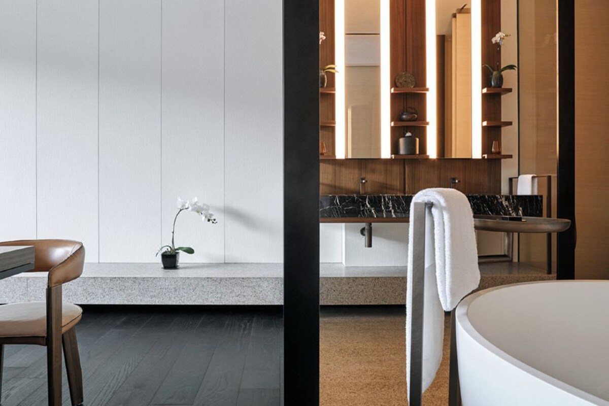 Ein modernes Badezimmer mit Marmorplatte, einer weißen Badewanne und einem Holzwaschtisch.