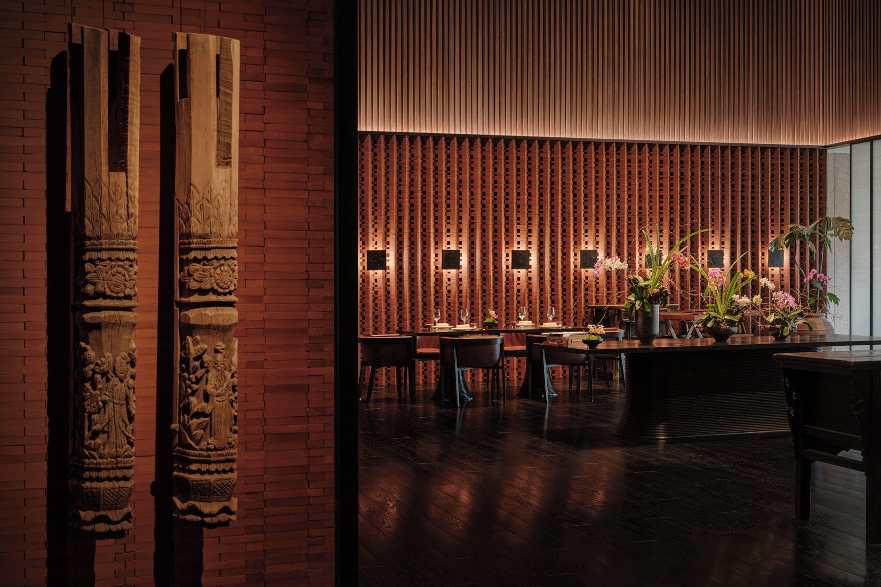 A restaurant with a brick wall, wooden columns, and a patterned ceiling.