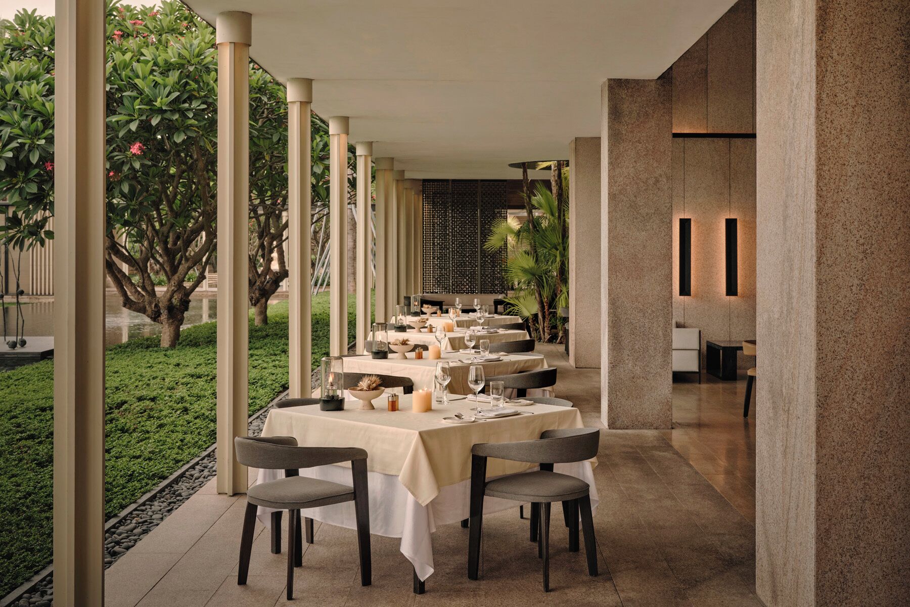 Un restaurante con terraza, mesas con manteles blancos y sillas.