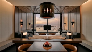 Un interior moderno con una mesa central, asientos y un amplio ventanal con vistas a la ciudad.