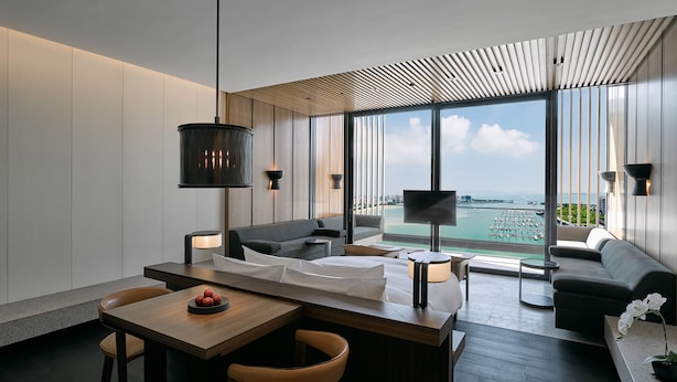 Habitación de hotel moderna con comedor, sofá y vistas a la ciudad.